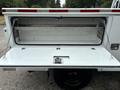 Rear view of a white 2013 Ford F-250 SD utility truck with an open compartment revealing a large storage area