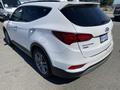 A white 2018 Hyundai Santa Fe parked with a slightly angled view showing the rear and side details of the vehicle