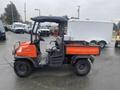 A red 2010 Kubota RTV 900 utility vehicle with a black canopy and open bed, featuring two seats in the front and rugged tires