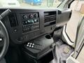 Interior dashboard of a 2013 Chevrolet Express featuring a radio climate controls and various buttons with a cup holder and floor mat visible