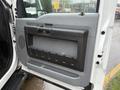 The interior door panel of a 2015 Ford F-450 featuring a black handle a textured grip and storage compartments