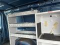A 2006 Ford Econoline van interior with empty shelves and storage compartments installed against the walls