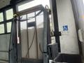 A wheelchair lift with a metal mesh platform and yellow safety handles installed in a 2007 Freightliner B2 bus