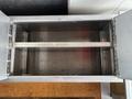 An empty metal storage compartment with a hinged lid and a central crossbar for support