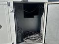A 2005 Freightliner M2 106 with an open storage compartment revealing tangled cables and electrical connections inside