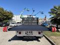 A 2020 Peterbilt 330 tow truck with a flatbed and red hooks at the rear facing directly towards the viewer