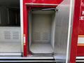 A red fire truck with a partially open storage compartment featuring a smooth interior and horizontal ventilation slots