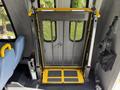 A foldable wheelchair ramp with a metal mesh design and yellow safety markings inside a 2013 Ford Econoline bus