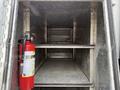 An empty metallic storage compartment of a vehicle with a fire extinguisher mounted on the side