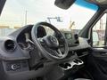Interior of a 2023 Mercedes-Benz Sprinter showcasing the steering wheel dashboard and center console with cup holders and control buttons