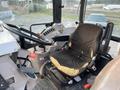 The interior of a Kubota M6040 tractor featuring a worn black driver's seat with visible damage and controls including a steering wheel and various levers
