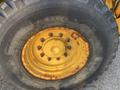 Close-up of a large tire on a Komatsu WB156PS-5 with visible rust on the rim and tread labeled TRI 2 STEEL