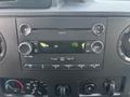 Dashboard controls of a 2013 Ford E-350 Super Duty featuring a radio display and various buttons for audio settings and climate control