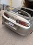 A silver 1997 Toyota Supra with a prominent rear spoiler and distinct tail lights featuring red and amber lenses