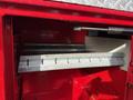 A metal storage compartment with a silver sliding shelf inside a red utility truck's body