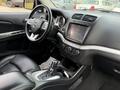 Interior view of a 2013 Dodge Journey featuring black leather seats a central touchscreen display and a gear shift in the foreground