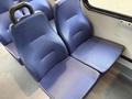 A blue fabric seat with a curved backrest designed for passenger comfort inside a vehicle