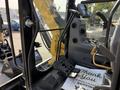 Interior view of a 2022 Caterpillar 306 showing the operator controls, foot pedals and display panel with a thank you note on the floor mat