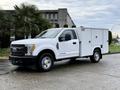 A white 2017 Ford F-350 SD truck with a service body and dual rear wheels parked at an angle facing left