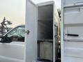 A 2009 Ford F-550 with an open truck bed reveal showing an empty storage compartment inside