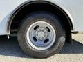 Side view of a 2019 Chevrolet Express wheel with a silver rim and black tire mounted on a light gray vehicle