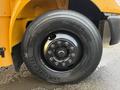 Close-up of a black tire mounted on a yellow truck showing detailed tread pattern and metal rim with visible lug nuts