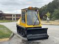 A yellow 2004 Bombardier SW48 with a front snowplow blade and tracks designed for snow removal and utility work