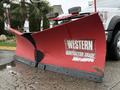 A red Western Contractor Grade snow plow attached to a Ford F600 vehicle