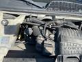 Engine compartment of a 2011 Chevrolet Express showing various components including hoses wires and an engine cover