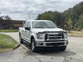 A white 2017 Ford F-150 pickup truck with chrome accents parked on a paved area showcasing its front view and distinctive grille