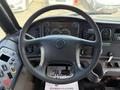 Steering wheel and dashboard of a 2011 Freightliner B2 displaying gauges dials and control buttons