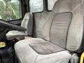 A beige cloth seat inside a 2003 Freightliner FL70 with textured fabric and a slightly worn appearance