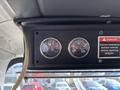 Dashboard of a 2011 Autocar Xpeditor showing two gauges for voltage and temperature alongside a warning label about vehicle clearance