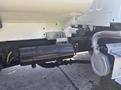 Close-up of the undercarriage of a 2022 Freightliner M2 106 showing various components including a black cylindrical tank attached to the chassis with visible pipes and wires