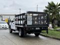 A white 2019 Ford F-350 SD with a black flatbed and metal cage on the back is parked with a tailgate up