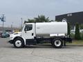 A 2006 Freightliner M2 106 truck with a silver tank mounted on the back viewed from the side