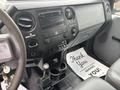 Interior view of a 2014 Ford F-550 dashboard featuring controls for radio and climate with a gear shifter and a thank you note on the floor mat