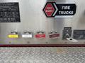 A metal panel featuring several colorful valves and labels for discharges and drains on a fire truck