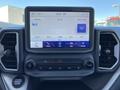 Image of a 2023 Ford Bronco Sport's dashboard displaying a digital screen with radio stations and various options for audio settings