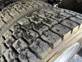 Close-up of a rugged tire tread with deep grooves showing significant wear and dirt on a 2014 Hino 195