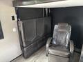 A brown leather reclining chair with a textured pattern and adjacent foldable seating in a travel trailer interior