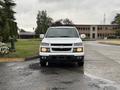 A white 2011 Chevrolet Colorado parked on a wet surface facing forward with its front grille and headlights visible