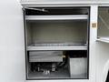 A 2001 Ford F-350 is parked with its utility door open revealing a spacious storage compartment containing equipment and a battery