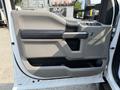 A close-up of the driver's side door panel of a 2020 Ford F-350 SD featuring a gray interior with a black handle and various control buttons