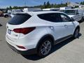 A white 2018 Hyundai Santa Fe parked with a sleek design featuring a rear spoiler and alloy wheels