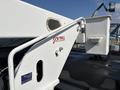 A close-up view of a white Freightliner M2 106 truck's lift gate with a warning label and a metal handrail attached