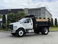 A 2017 Ford F-750 in white with a dump bed raised on the back parked on a lot
