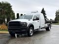 A white 2024 RAM 5500 truck with a sleek design and a prominent grille featuring the RAM logo parked on a roadway