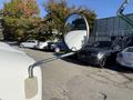 A side mirror of a 2012 Freightliner M2 106 reflecting nearby vehicles and trees