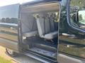 A 2016 Ford Transit 150 with an open side door revealing several gray seats arranged in rows inside the vehicle